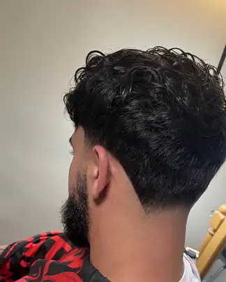 Curly top with a low taper and beard trim, cut at Studio K