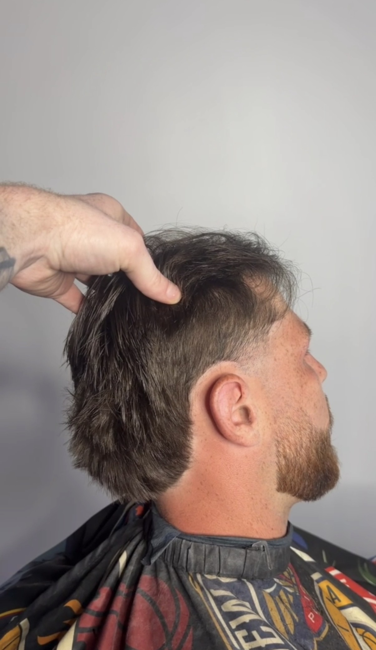 Long textured back with tapered sides and a defined beard, cut at Studio K